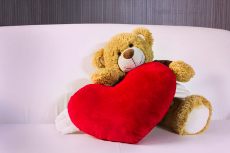 Lovely brown bear gift doll an red hearts on sofa の写真素材