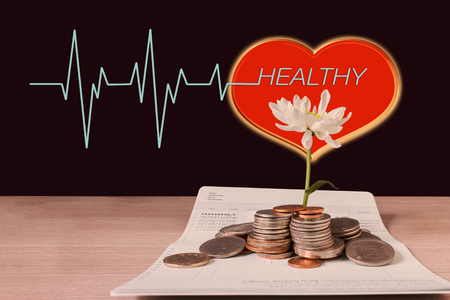 Coins and flower on book bank account and red heart pulse with text healthyの写真素材