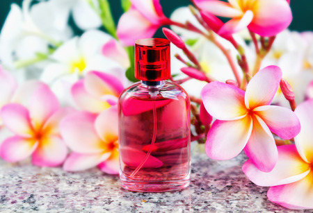 Single bottle of sweet pink fragrant perfume decorated with pink flower plumeriaの写真素材