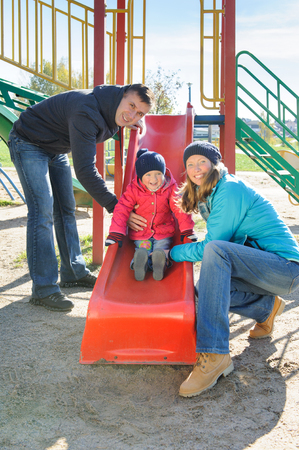 Parents with daughter playing at childrens slideの写真素材