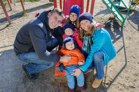 Happy smiling young family of five at childrens playground in parkの写真素材