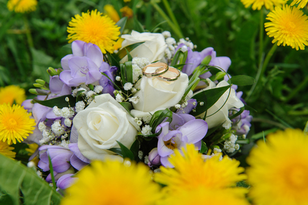 Wedding bouquet and wedding rings in dandelionsの写真素材