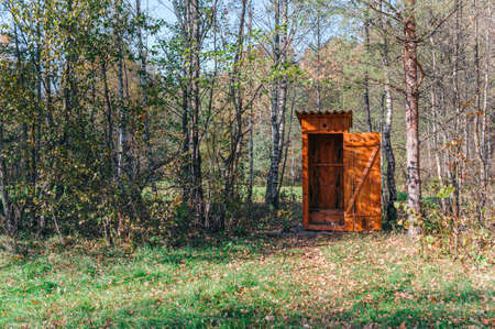 Opened wooden WC toilet cabin in a golden forest national park , close-up. Autumn landscape. Seasons, ecology, ecotourism, environmental conservation, architectureの写真素材