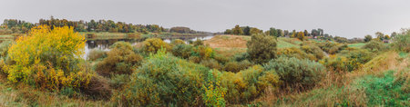 Autumn landscape panorama photography, the European part of the Earth. Druya, Belarus. Rural landscape with a rainy sky. Green field and village on the horizonの写真素材