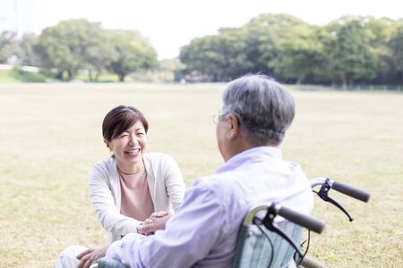 Nursing Care Image, Elderly and Helper in Wheelchair, Walking in the Parkの写真素材
