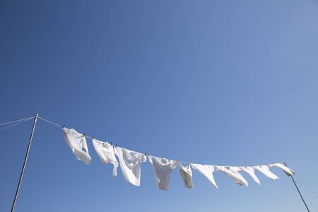Laundry that flutters in the wind in the clear blue skyの写真素材
