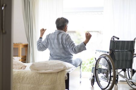 Elderly man looking out in pajamasの写真素材