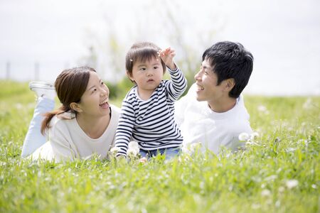 Japanese young family playing on the grass in the parkの写真素材