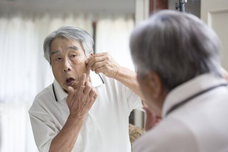 An old man who is anxious about his complexion in the mirrorの写真素材