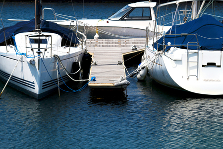A summer view where the white yacht moored on the pier of the marina shines on the surface of the waterの写真素材