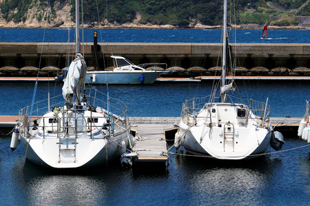 A summer view where the white yacht moored on the pier of the marina shines on the surface of the waterの写真素材