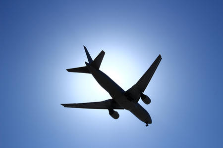 A silhouette of an airliner flying under the back light sunの写真素材