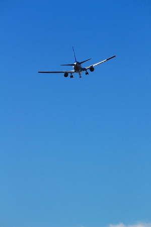 The back of an airplane flying in the blue skyの写真素材