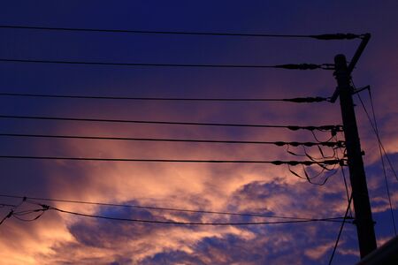 Purple and orange sunset sky and power poleの写真素材