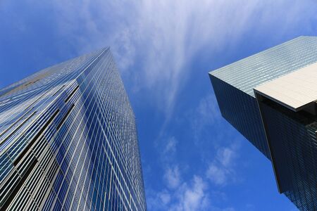 Landscape of two skyscrapers with different designs standing under the blue skyの写真素材