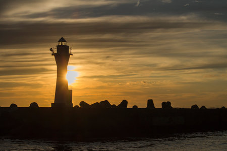 Kushiro Port Lighthouse where the silhouette is projected in the orange sky at sunsetの写真素材