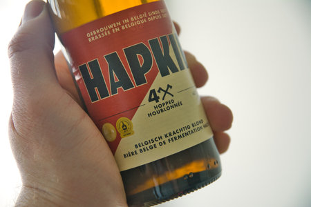 Antwerp, Belgium, February 2021: Illustrative Editorial: Hapkin Belgian beer held by hand. Strong blonde, hopped. Bottle and label.のeditorial素材