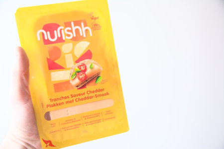 Antwerp, Belgium, March 2021, Illustrative Editorial: Hand holding Nurishh Vegan alternative for cheddar cheese slicesのeditorial素材