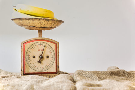 Bananas on a vintage and retro weighing scale with white background and copy space. Fruit balanceの写真素材
