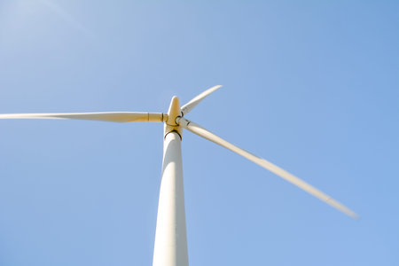 Close-up and low angle view of spinning blades of a wind turbine generating renewable and low carbon...
