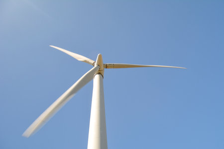 Close-up and low angle view of spinning blades of a wind turbine generating renewable and low carbon energyの写真素材