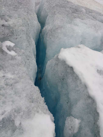 Crack in the ice of a glacier due to global warming and climate change. Melting snow causing sinkhole.の写真素材