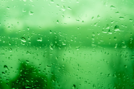 Raindrops on a window, illustrating gray and rainy weather during the day. Black and white grayscale.の写真素材