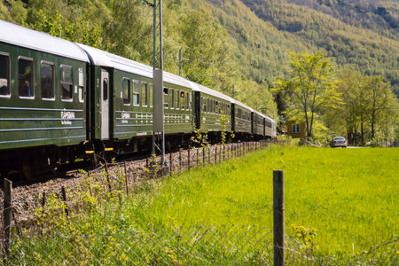 Flam, Norway, May 2015: train carriages of the Flamsbana (Flam Line) running through a green valley. Flam railway is a railway line between Myrdal and FlÃ¥m in Aurland, Norway.のeditorial素材