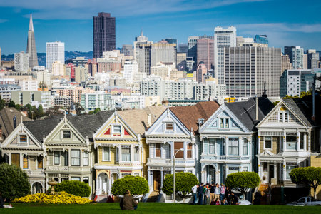 San Francisco, California, United States, November 2013: View on the Painted Ladies Victorian houses of San Francisco with cityscape and skyline in the background on a blue sky. People sitting frontのeditorial素材