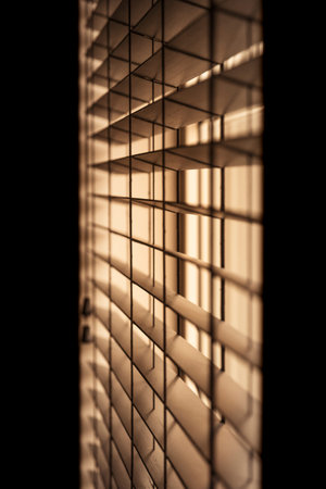 Vertical shot of venetian blinds creating a moody and noir inspired atmosphere with light...