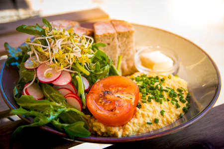 Healthy vegan breakfast. Scrambled Tofu as egg replacement with tomato, salad, radish and bread and plant-based butterの写真素材