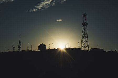 Silhouette of communication tower pylons against a sunset.の写真素材