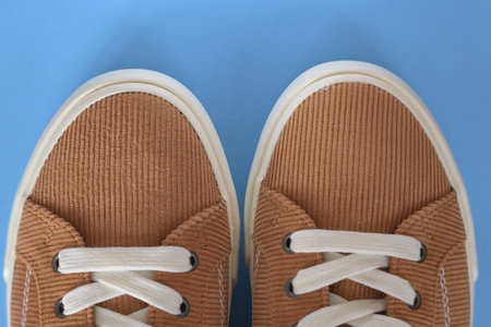 Closeup of beige corduroy sneaker shoes on a blue backgroundの写真素材