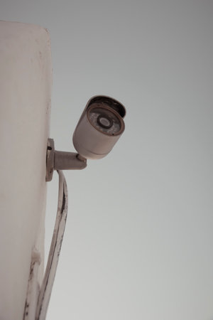 Vertical shot of a domestic security camera mounted against a wall protecting against burglaryの写真素材