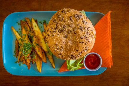 Directly above shot of basic fast food: hamburger with french fries and ketchup on a blue plate with orange napkinsの写真素材