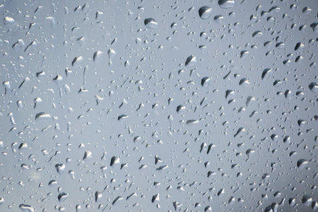 Rain drops on a window indicating gray and rainy dayの写真素材
