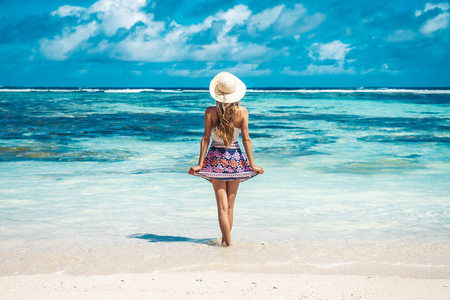 A young girl standing in shallow water on La Digue island, Seychellesの写真素材