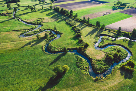 A winding river surrounded by green meadowsの写真素材