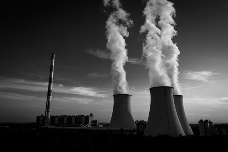 A Power plant with white smoke over its chimneysの写真素材