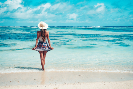 A young girl standing in shallow water on La Digue island, Seychellesの写真素材