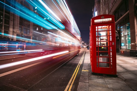 Light trails of a double decker bus next to the iconic telephone booth in Londonの写真素材