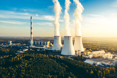 A Power plant with white smoke over its chimneysの写真素材