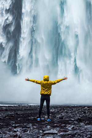 A person admirnig the beauty of Skogafoss waterfall located in Icelandの写真素材