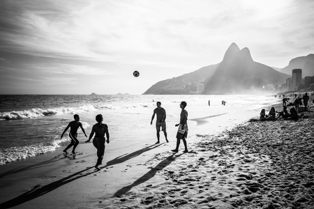 RIO DE JANEIRO, BRAZIL - FEBRUARY 24, 2015: A group of Brazilians playing on the shore of Ipanema Beach, with the famous Dois Irmaos mountain behind themのeditorial素材