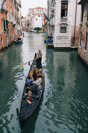 VENICE, ITALY - MAY 5, 2018: A group of tourists travelling in a Gondola through beautiful canals of Venice, Italyのeditorial素材