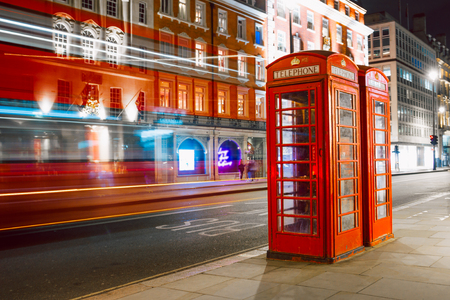 Light trails of a double decker bus next to the iconic telephone booth in Londonの写真素材