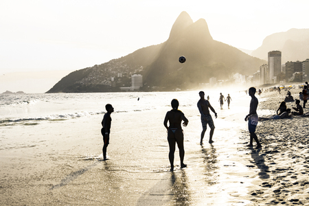 RIO DE JANEIRO, BRAZIL - FEBRUARY 24, 2015: A group of Brazilians playing on the shore of Ipanema Beach, with the famous Dois Irmaos mountain behind themのeditorial素材