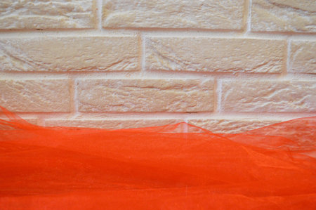 Beige brick wall with a red cloth. Large bricks. The background.の写真素材