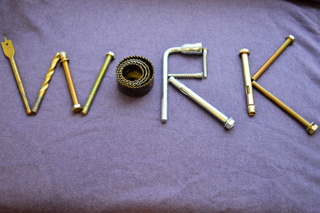 The inscription work is written by metal anchor bolts, screws, svermami, wrenches. Work made up of objects. The word work is made up of a metalwork tool on a purple background.の写真素材