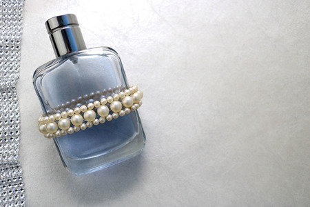 Blue beautiful glass transparent fashionable glamorous bottle of cologne, perfume with white gems and a place for a simple text on a light white background.の写真素材